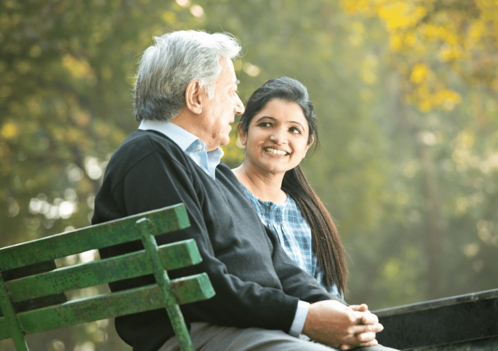 Caregiver sitting with elderly man outdoors