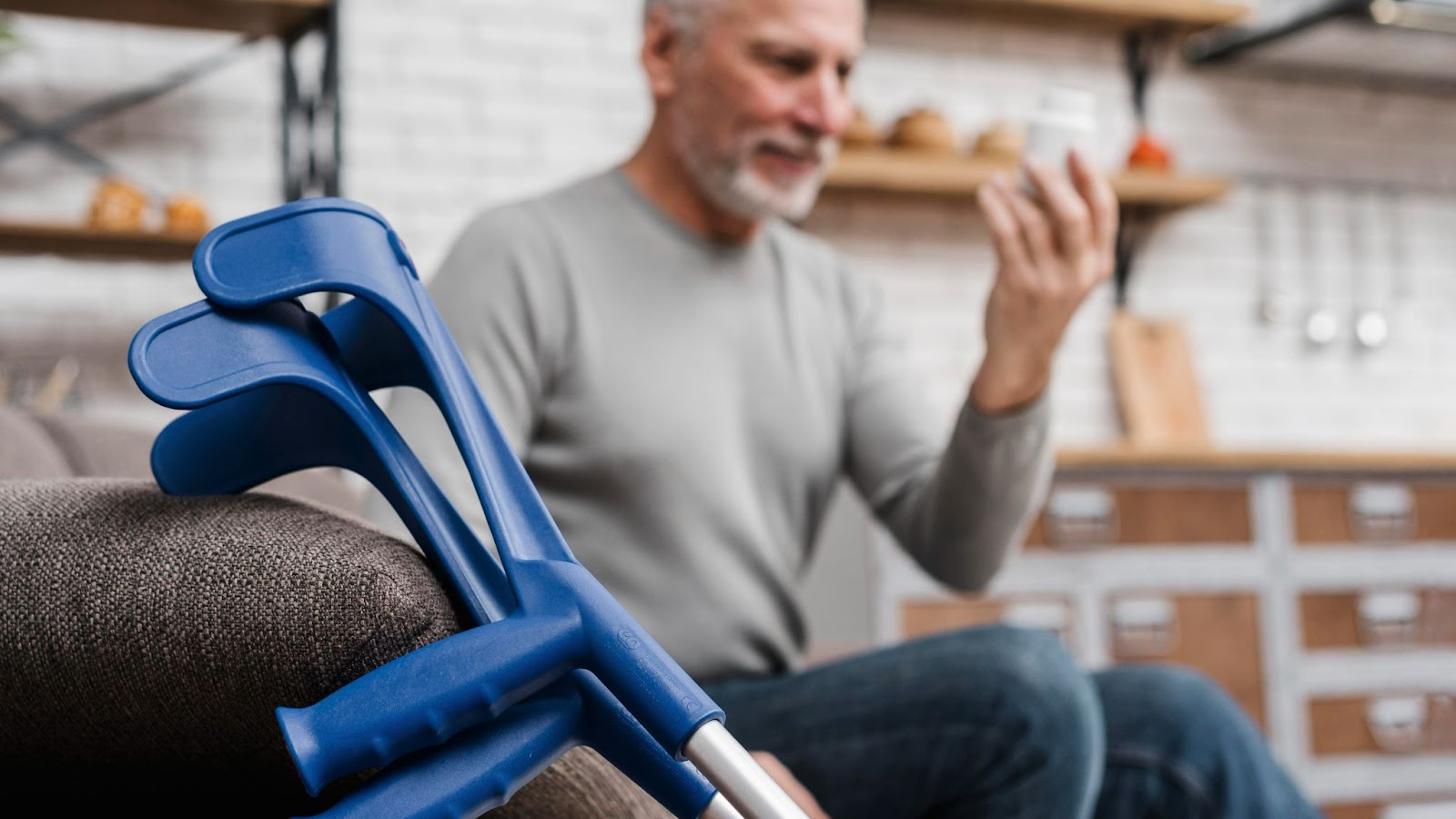 An elderly an with crutches resting, checking on his hand for general mobility physiotherapy