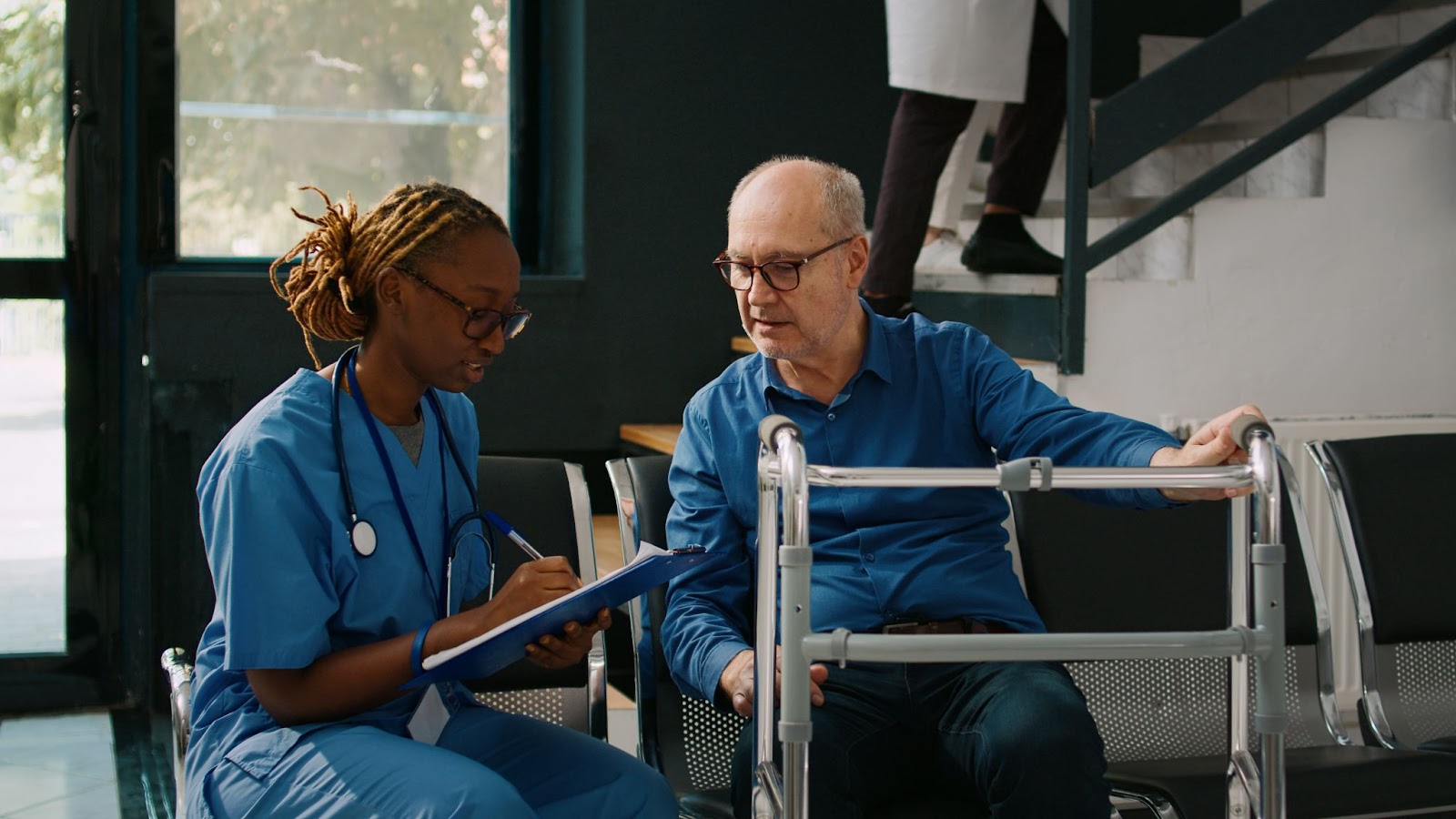 Nurse consulting elderly man with walker in healthcare facility, highlighting aged care workforce shortage