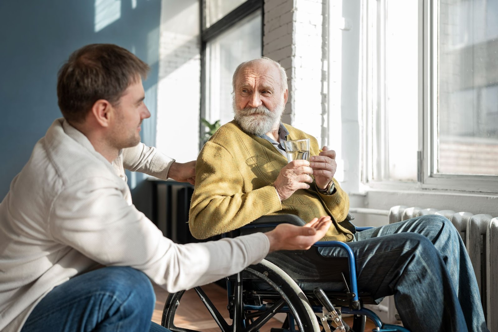 Middle-aged man assisting elderly man in wheelchair at home, representing aged care workforce shortage