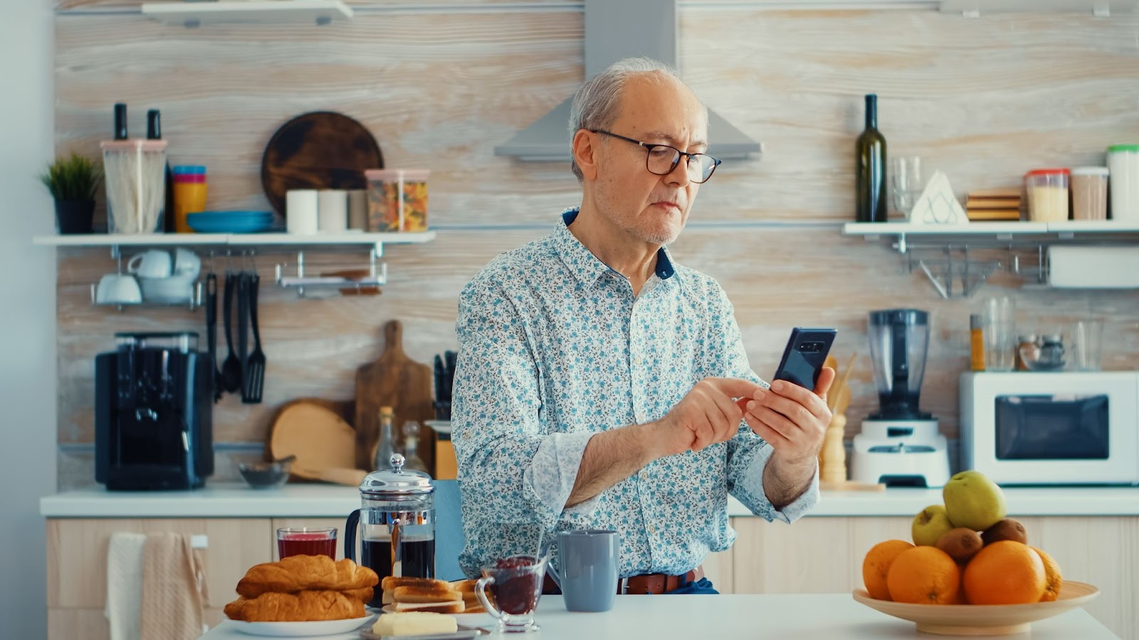 Senior man checking recipes on smartphone to assist with meal planning in a modern kitchen