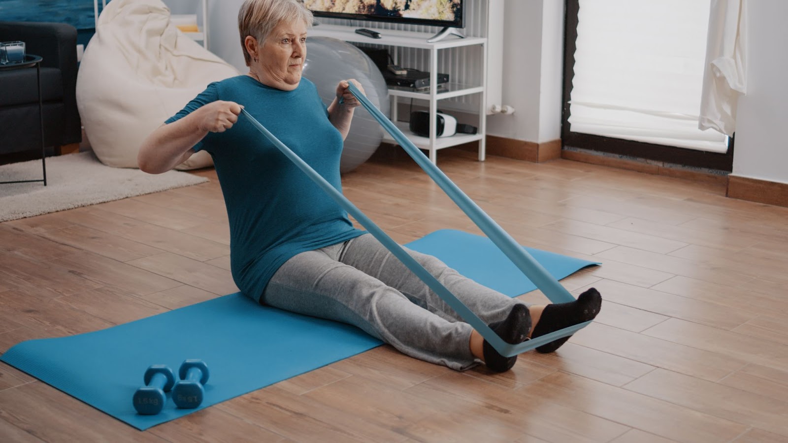 Senior woman doing physiotherapy exercises at home with a resistance band to strengthen muscles safely